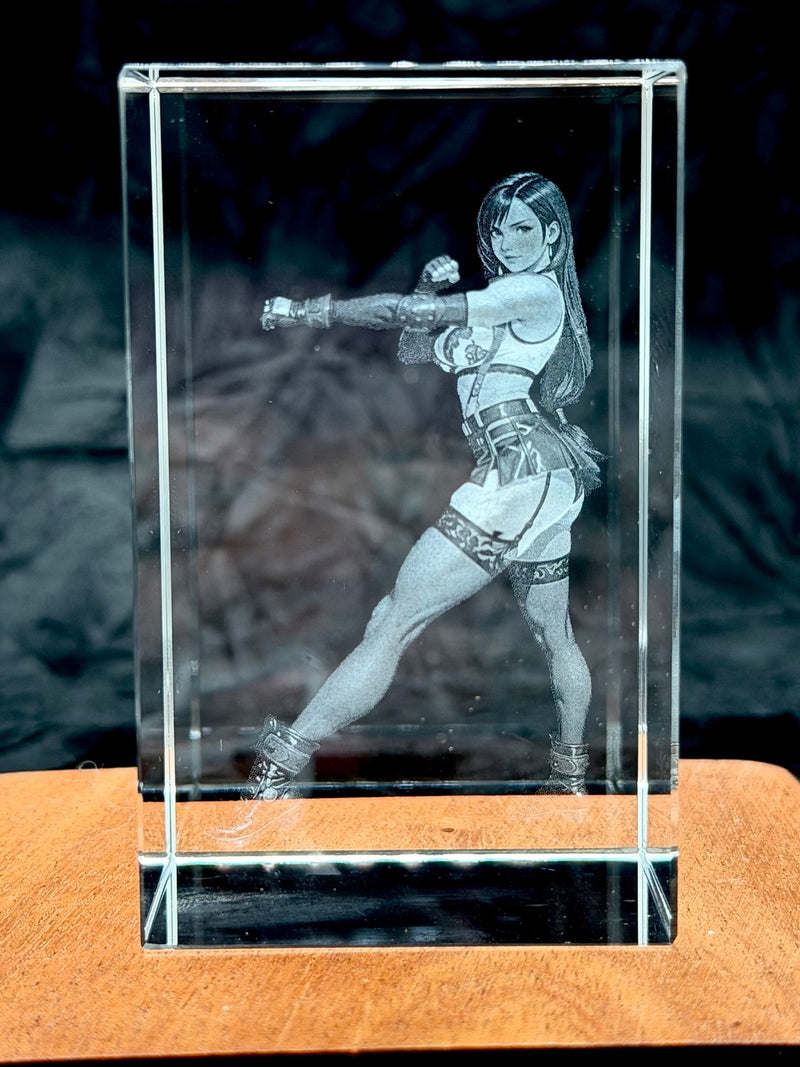 Crystal block with a laser-engraved image of a woman in a dynamic pose on a wooden surface.